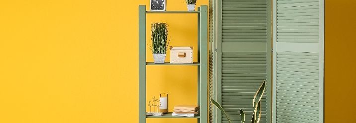 Grüner Raumteiler und grünes Regal vor gelber Wand